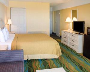 Quality Inn & Suites Oceanfront في فرجينيا بيتش: غرفة فندقية بسرير وتلفزيون بشاشة مسطحة