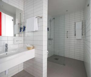 uma casa de banho branca com um lavatório e um chuveiro em Park Inn by Radisson Sheremetyevo Airport Moscow em Khimki