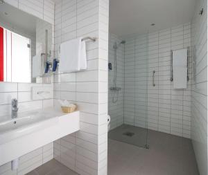 a white bathroom with a sink and a shower at Park Inn by Radisson Sheremetyevo Airport Moscow in Khimki