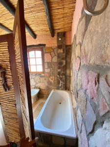 La salle de bains est pourvue d'une baignoire dans un mur en pierre. dans l'établissement hosteria castillos de huichaira, à Maimará