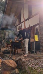 a man cooking food on top of a grill at CABAÑA MÁGICA CUCUNUBA in Cucunubá