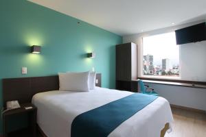 1 dormitorio con 1 cama grande y pared azul en One Periferico Sur, en Ciudad de México