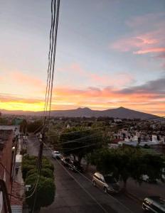 um pôr-do-sol sobre uma cidade com carros estacionados numa rua em Casa Celeste em Morelia
