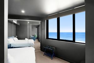 a bedroom with two beds and a view of the ocean at 703 Luxury Ocean View Apartment in Newcastle