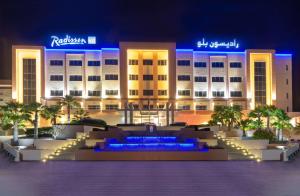 Radisson Blu Hotel & Resort, Sohar في صحار: فندق فيه نافورة امام مبنى