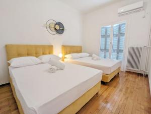 two beds in a room with white walls and wooden floors at Athens Divas Soul Suite in Athens