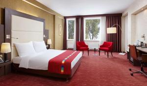 a hotel room with a large bed and red chairs at Park Inn by Radisson Odintsovo in Odintsovo
