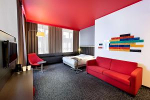 a hotel room with a red couch and a bed at Park Inn by Radisson Central Tallinn in Tallinn