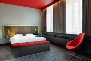 a hotel room with a bed and a red chair at Park Inn by Radisson Central Tallinn in Tallinn