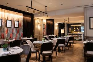 um restaurante com mesas e cadeiras num quarto em Holmes Hotel London em Londres