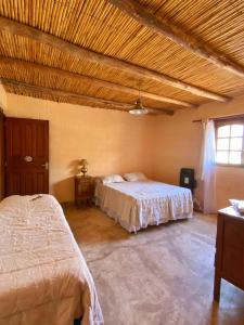 - une chambre avec deux lits et un plafond en bois dans l'établissement hosteria castillos de huichaira, à Maimará