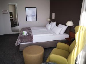 une chambre d'hôtel avec un lit et une chaise dans l'établissement First Inn Hotel Zwickau, à Zwickau