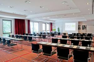 una sala de conferencias con mesas, sillas y una pantalla en First Inn Hotel Zwickau, en Zwickau
