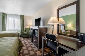 a hotel room with a bed and a desk with a mirror at Quality Inn in Russell