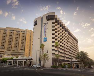 ein hohes weißes Gebäude in einer Stadtstraße mit Palmen in der Unterkunft Radisson Blu Hotel, Dubai Deira Creek in Dubai