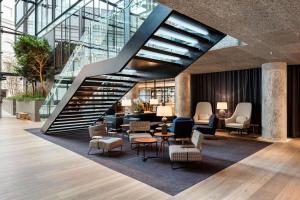 a lobby with a staircase with chairs and tables at The Edwardian Manchester, A Radisson Collection Hotel in Manchester