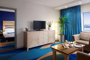 a living room with a tv on a dresser and a bed at Radisson Blu Hotel, Liverpool in Liverpool