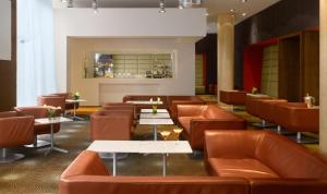 a restaurant with brown leather chairs and tables at Radisson Blu Hotel, Liverpool in Liverpool