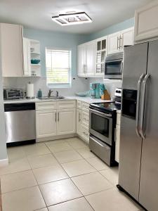 una cocina con armarios blancos y electrodomésticos de acero inoxidable en SeaSide Townhome, Spacious 2br 3bath Leeward Grace Bay, Providenciales, walk to beach en Providenciales