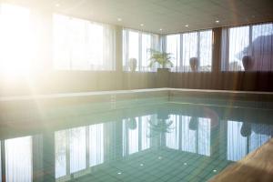 a swimming pool with the sun shining through the windows at Radisson Blu Arlandia Hotel, Stockholm-Arlanda in Arlanda