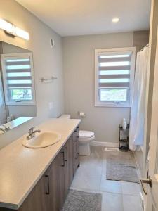 een badkamer met een wastafel en een toilet en 2 ramen bij Ottawa-Rockland Newly-built 4 beds house in Rockland
