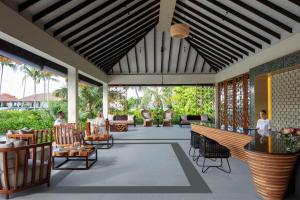 a lobby of a resort with people sitting in chairs at Radisson Blu Resort Maldives in Fenfushi