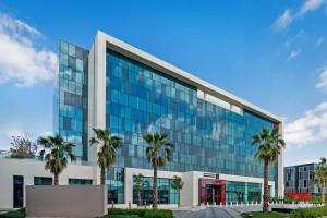 an office building with palm trees in front of it at Radisson RED Dubai Silicon Oasis in Dubai