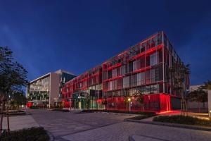 Radisson RED Dubai Silicon Oasis في دبي: مبنى به انارة حمراء على جانبه