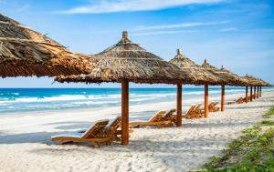 een rij rieten parasols en stoelen op een strand bij Radisson Blu Resort Cam Ranh in Cam Ranh