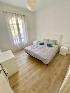 a white bedroom with a bed and a wooden floor at Central Apartment BCN in Barcelona