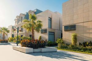 a building with a palm tree in front of it at Mansard Riyadh, a Radisson Collection Hotel in Riyadh