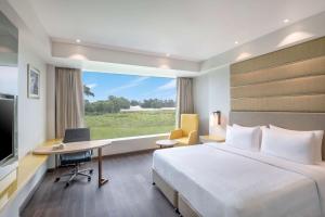 a hotel room with a bed and a desk and a window at Radisson Hotel Bareilly Airport in Bareilly