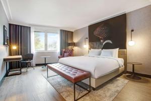 Radisson RED London Heathrow في هارموندسورث: غرفة فندقية بسرير كبير وكرسي