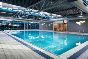 a large swimming pool with blue water in a building at Radisson RED London Heathrow in Hillingdon