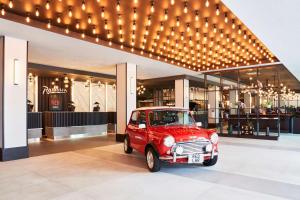 ウェスト・ドレイトン、ロンドンにあるRadisson RED London Heathrowの建物前に停車した古い赤い車