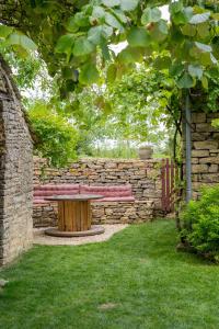 a wooden bench in a garden with a stone wall at A PAS DE LOUP, Maison de charme sur domaine viticole in Chaux