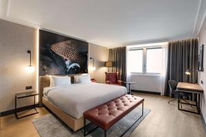 a hotel room with a large bed and a desk at Radisson RED London Heathrow in Hillingdon +73 photos