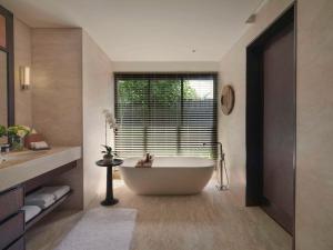 a bathroom with a tub and a large window at Raffles Bali in Jimbaran
