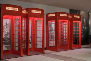 four red phone booths are lined up in a room at Radisson RED London Heathrow in Harmondsworth