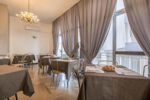 uma sala de jantar com mesas, cadeiras e janelas em Hotel Lily em Rimini