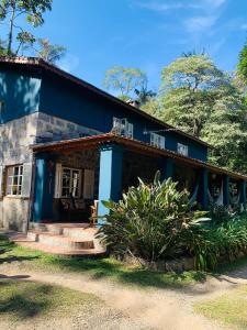 a blue house with a porch at Quarto em Residência Familiar - Itatiaia in Itatiaia