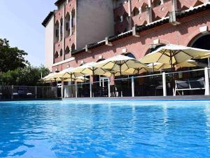 un hôtel avec une piscine bordée de parasols dans l'établissement Novotel Toulouse Centre Compans Caffarelli, à Toulouse