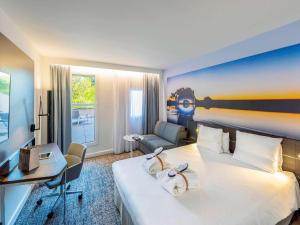 トゥールーズにあるノボテル トゥールーズ サントル コンパン カッファレッリの大きなベッドとデスクが備わるホテルルームです。