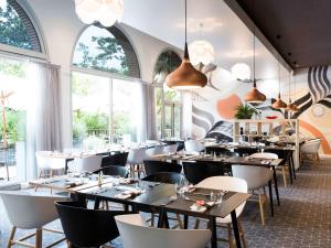 - une salle à manger avec des tables, des chaises et des fenêtres dans l'établissement Novotel Toulouse Centre Compans Caffarelli, à Toulouse