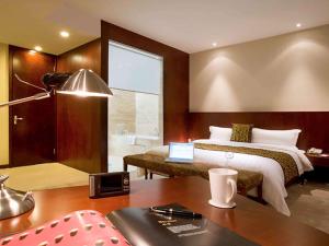 a bedroom with a bed and a desk with a laptop at Mercure Wanshang Beijing in Beijing