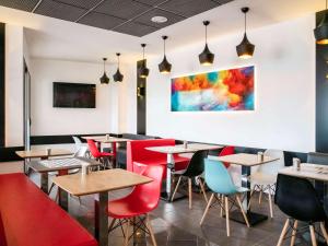 un restaurante con mesas y sillas y una pintura en la pared en IBIS Cannes Mouans Sartoux Piscine parking gratuit en Mouans-Sartoux