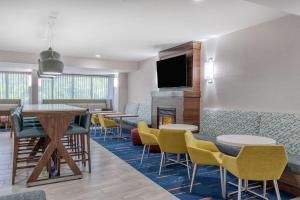 a waiting room with tables and chairs and a fireplace at Hampton Inn New Philadelphia in New Philadelphia