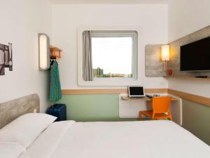 a bedroom with a bed and a desk with a laptop at ibis budget Campinas Aquidaban in Campinas