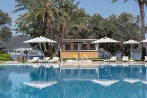 a swimming pool with chairs and umbrellas at DoubleTree by Hilton Bodrum Isil Club Ultra All-Inclusive Resort in Torba