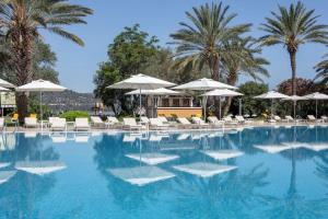 a swimming pool with chairs and umbrellas and palm trees at DoubleTree by Hilton Bodrum Isil Club Ultra All-Inclusive Resort in Torba
